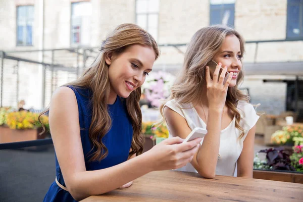 Mujeres jóvenes con teléfonos inteligentes y café en la cafetería — Foto de Stock