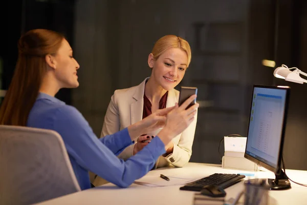 Forretningskvinner med smarttelefon sent på kveldskontoret – stockfoto