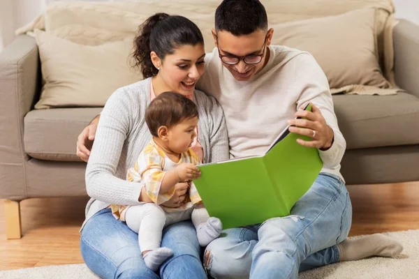 Lycklig familj med baby läsebok hemma — Stockfoto