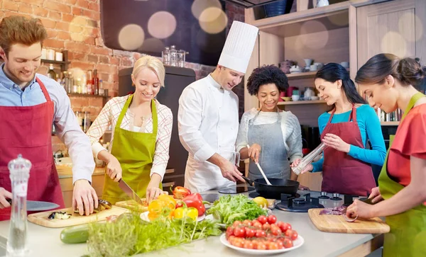 Amigos felices y cocinero cocinar en la cocina —  Fotos de Stock