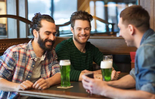 Amici con smartphone bere birra verde al pub — Foto Stock