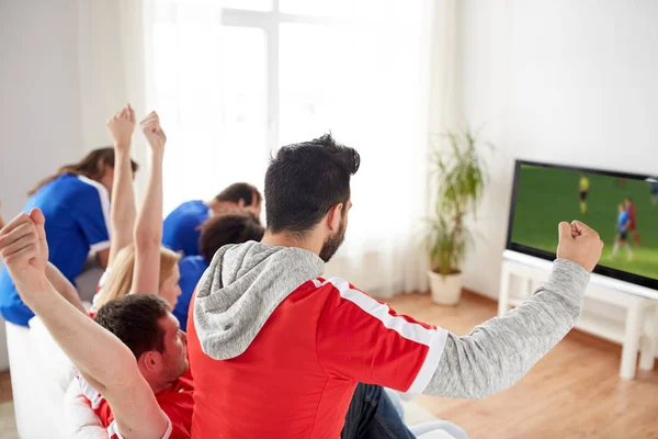 De ventilators van de voetbal kijken naar voetbalwedstrijd op tv thuis Stockfoto