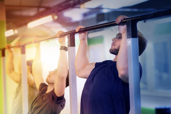 Group of young men doing pull-ups in gym — Stock Image Group of young men doing pull-ups in gym Stock Image