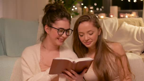 Felizes amigos do sexo feminino ler livro em casa — Vídeo de Stock