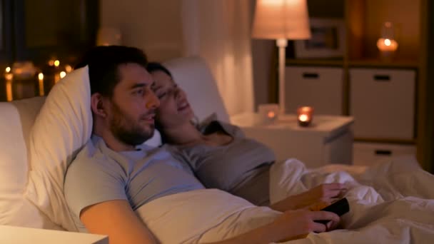 Feliz pareja viendo la televisión en la cama en casa — Vídeo de stock
