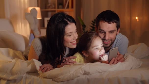 Família feliz com smartphone na cama em casa — Vídeo de Stock