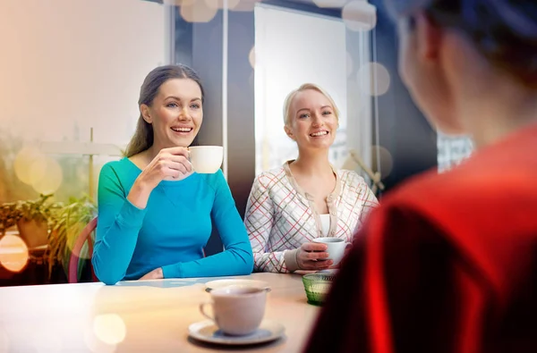 Jovens mulheres felizes bebendo chá ou café no café — Fotografia de Stock