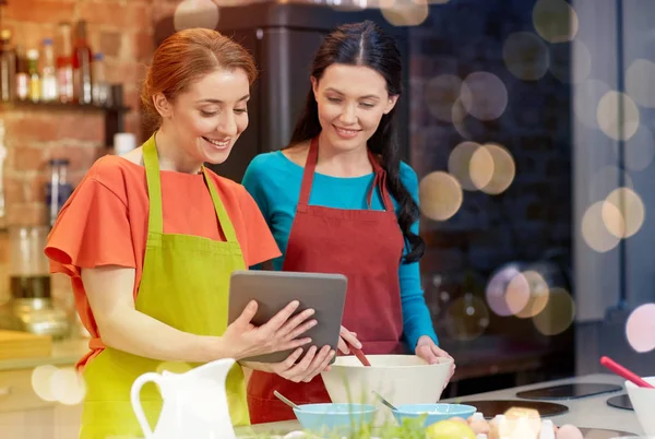 Mulheres felizes com tablet pc cozinhar na cozinha — Fotografia de Stock