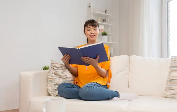 Genç Asyalı kadın okuma kitabı evde gülümseyen — Stok fotoğraf