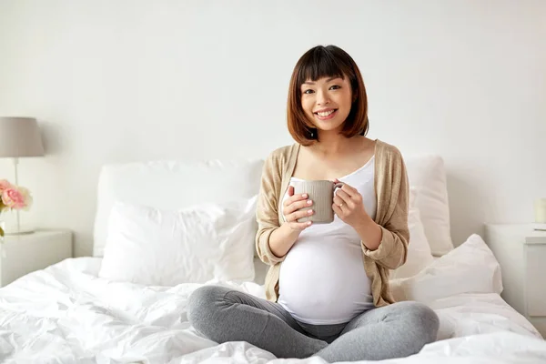 Glücklich schwangere Frau mit Tasse Tee zu Hause trinken — Stockfoto