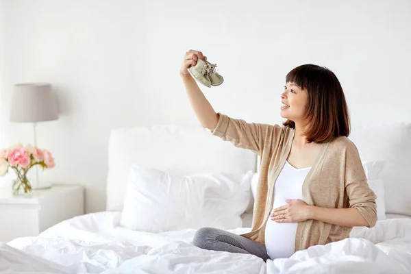 Glad gravid kvinna med Stövletter i sängen hemma — Stockfoto