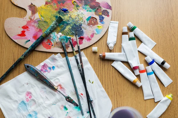 Palette knife, brushes and paint tubes on table — Stock Photo, Image