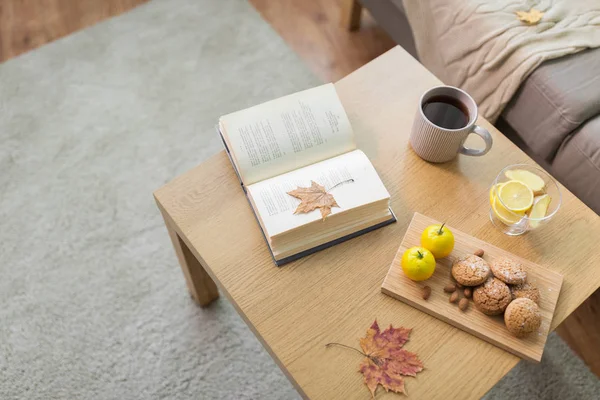 Boek, citroen, thee en koekjes op tafel thuis — Stockfoto