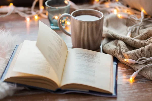 Livro e xícara de café ou chocolate quente na mesa — Fotografia de Stock