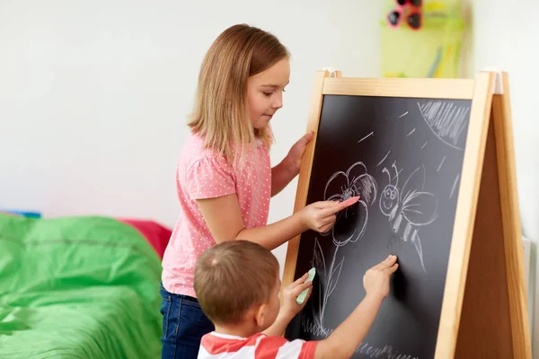 Happy kids drawing on chalk board at home — Stock Photo, Image