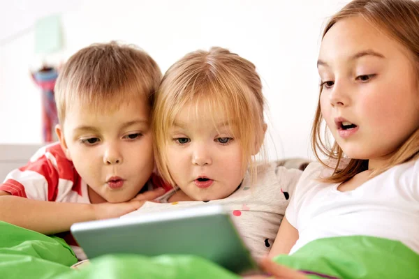 Küçük çocuklar evde yatakta tablet pc ile — Stok fotoğraf