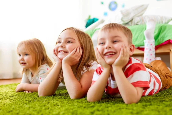 Niños pequeños y felices tumbados en el suelo o la alfombra — Foto de Stock