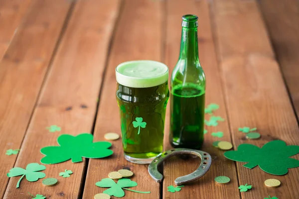 Vaso de cerveza verde, herradura y monedas de oro — Foto de Stock