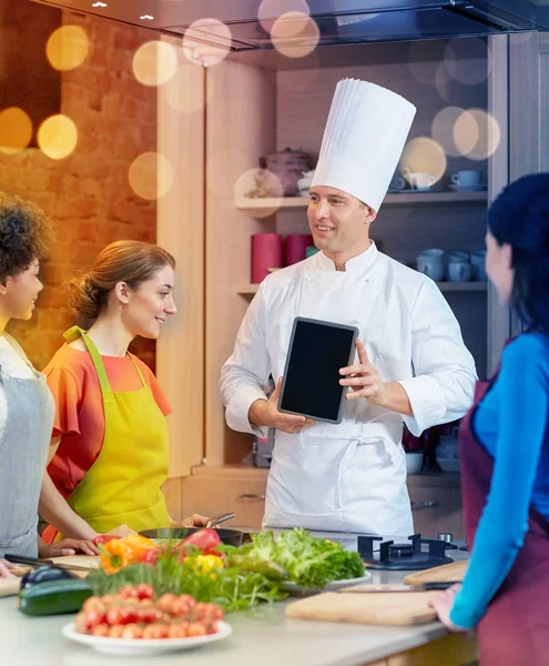 Щасливі жінки з шеф-кухарем і планшетним ПК на кухні — стокове фото