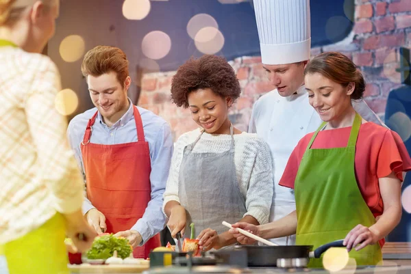 Happy friends and chef cook cooking in kitchen — Stock Photo, Image