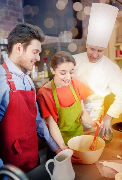 Gelukkige paar en mannelijke chef kok koken in de keuken — Stockfoto