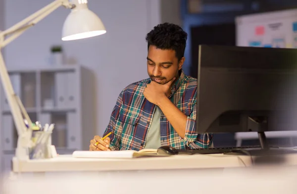 Creative man with notebook working at night office — Stock Photo, Image