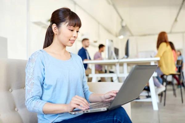 Счастливая азиатская женщина с ноутбуком работает в офисе — стоковое фото