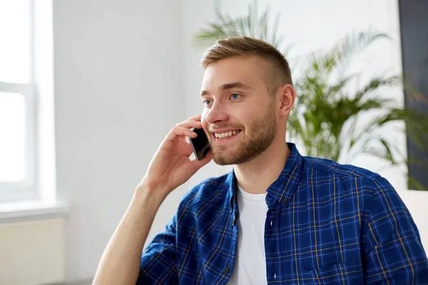 Sonriente joven llamando en el teléfono inteligente en la oficina — Foto de Stock