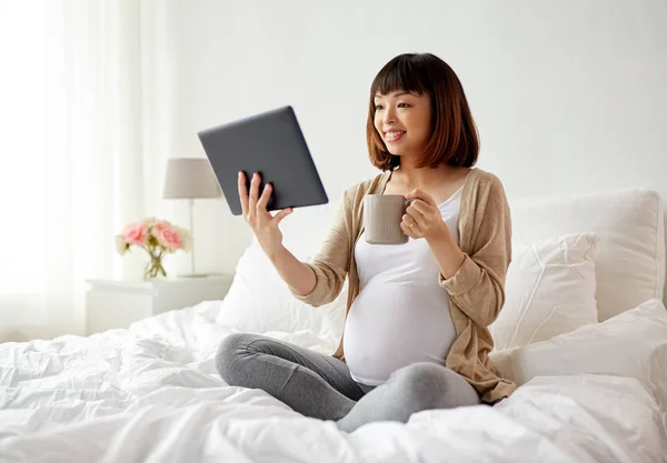 Gelukkig zwanger aziatische vrouw met tablet pc thuis — Stockfoto