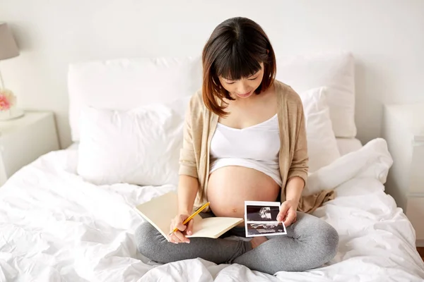Donna incinta con ecografia fetale a casa — Foto Stock