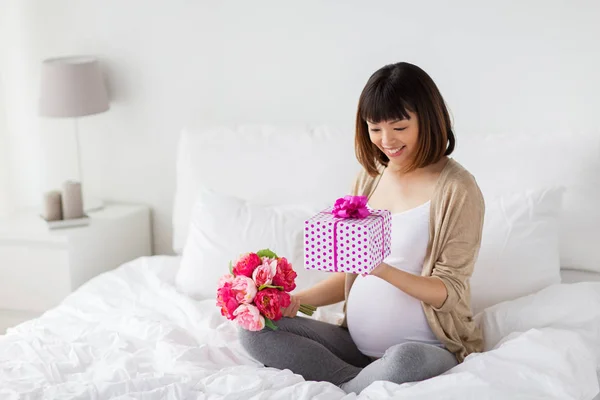 Szczęśliwy asian Kobieta w ciąży z prezent i kwiaty — Zdjęcie stockowe