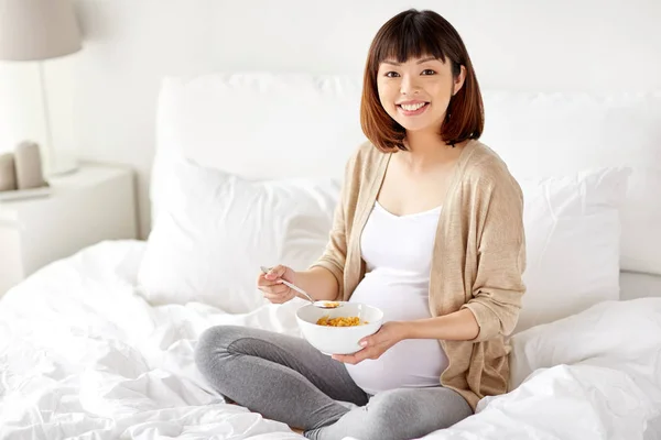 Mulher grávida feliz comer flocos de cereais em casa — Fotografia de Stock