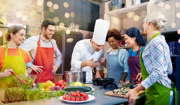 Amigos felizes e cozinheiro chef cozinhar na cozinha — Fotografia de Stock