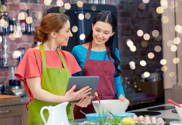 Happy women with tablet pc cooking in kitchen — Stock Photo, Image