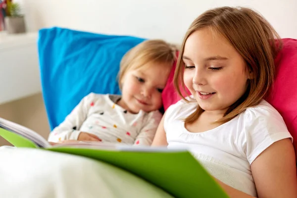 Weinig meisjes of zusters lezen boek in bed — Stockfoto