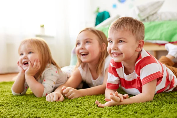 Niños pequeños y felices tumbados en el suelo o la alfombra — Foto de Stock