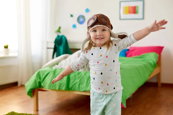 Счастливая маленькая девочка в пилотской шляпе играет дома — стоковое фото