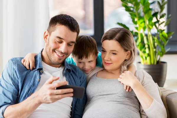 Счастливая семья со смартфоном дома — стоковое фото