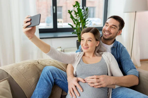 男人和怀孕的女人在家采取自拍照 — 图库照片