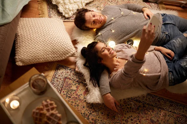 Пара лежит на полу и делает селфи дома — стоковое фото
