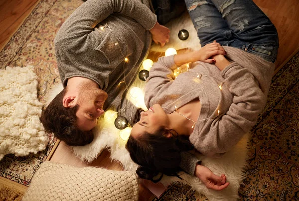 Szczęśliwa para z girlandą leżąca na podłodze w domu — Zdjęcie stockowe