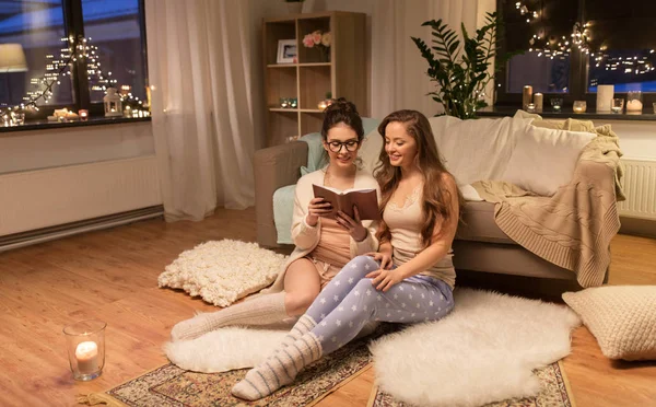 Happy female friends reading book at home — Stock Photo, Image