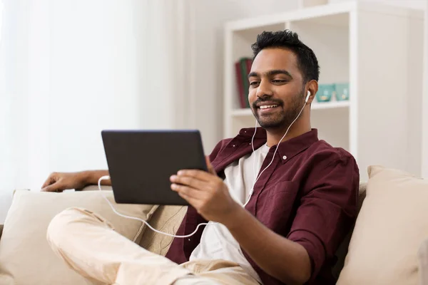 Hombre en auriculares con tablet pc escuchando música —  Fotos de Stock