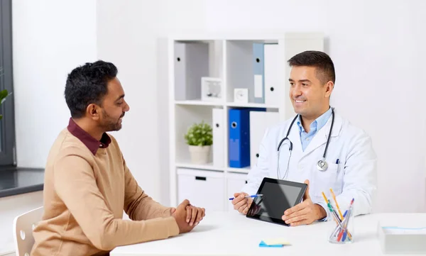 Счастливый врач с планшетным ПК и пациент в клинике — стоковое фото