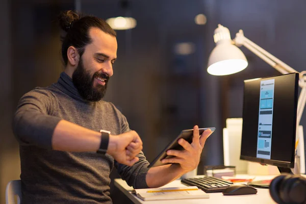 Ο άνθρωπος με το smartwatch και tablet pc στο γραφείο το βράδυ — Φωτογραφία Αρχείου