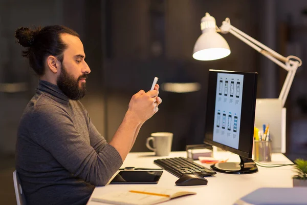 Creatieve man met smartphone bij nacht kantoor — Stockfoto