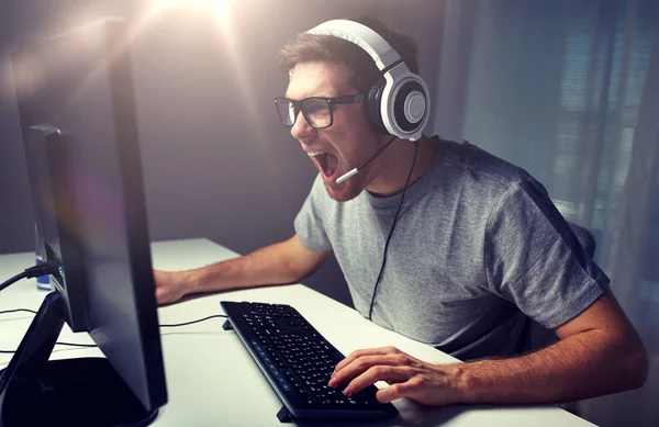 Homem em fone de ouvido jogando jogo de computador em casa — Fotografia de Stock