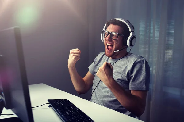 Man in headset playing computer video game at home — Stock Photo, Image