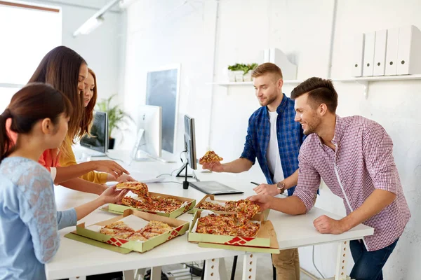 Equipe de negócios feliz comer pizza no escritório — Fotografia de Stock