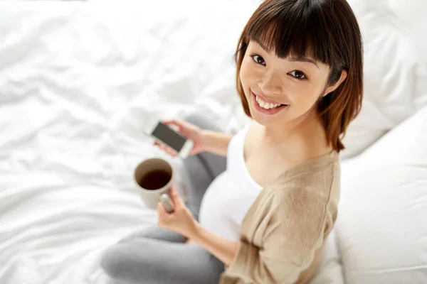 Mujer embarazada feliz con taza de té en la cama —  Fotos de Stock